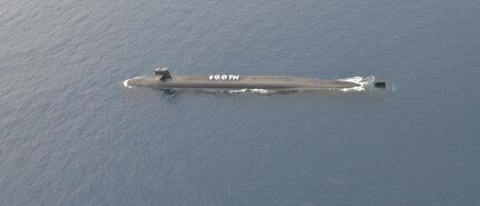 (June 15, 2017) Sailors assigned to the Ohio-class ballistic-missile submarine USS Alaska (SSBN 732) assemble topside to commemorate the submarine’s 100th patrol following a medical evacuation exercise with a U.S. Coast Guard HH-65 “Dolphin” helicopter.