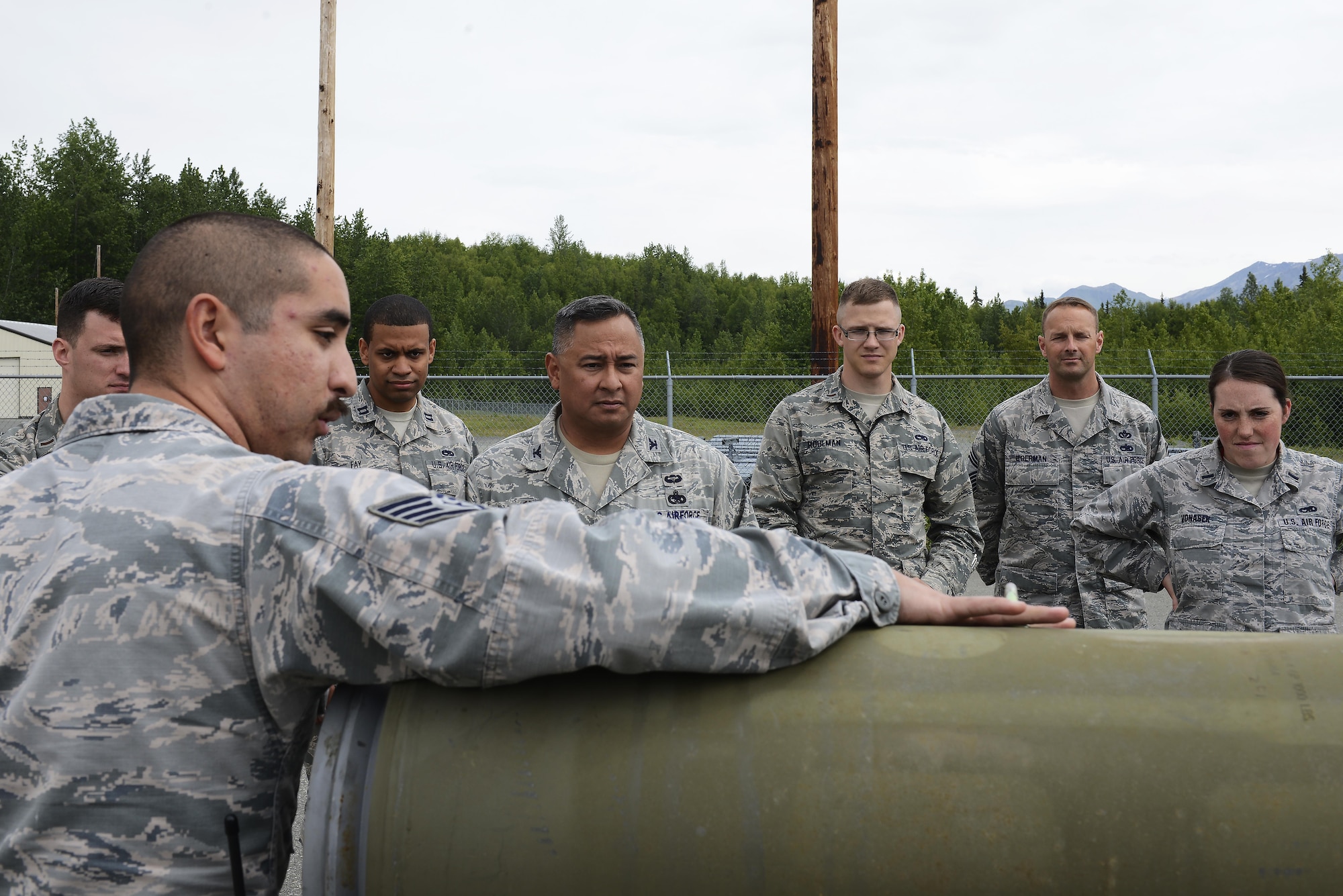 U.S. Air Force Staff Sgt. Michael Ramirez, munitions crew chief with the 3rd Munitions Squadron, explains the process of building a Joint Direct Attack Munition Guided Bomb Unit to Air Force Col. Frank Flores, commander Pacific Air Forces regional support center, and a group of company-grade officers at Joint Base Elmendorf-Richardson, Alaska, June 19, 2017. Bomb builds provide training and certification for 230 personnel within 3rd MUNS and keeps the squadron compliant, lethal and ready. 