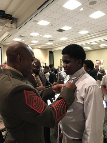 Marine Corps Logistics Base Albany Sgt. Maj. Johnny L. Higdon, teaches a young man how to properly tie a necktie during the 5th annual “Ties that Bind” event.  A group of Marines took part in “Ties that Bind,” a mentoring event that teaches young boys to tie a necktie while forming bonds with some of the community’s most distinguished leaders at the Phoebe Northwest Conference Center in Albany, Ga., June 15.  The annual event, hosted by Phoebe Putney Memorial Hospital’s Network of Trust School Health Program, selects 50 boys, mostly from homes without fathers, and pairs them with 50 local men.  