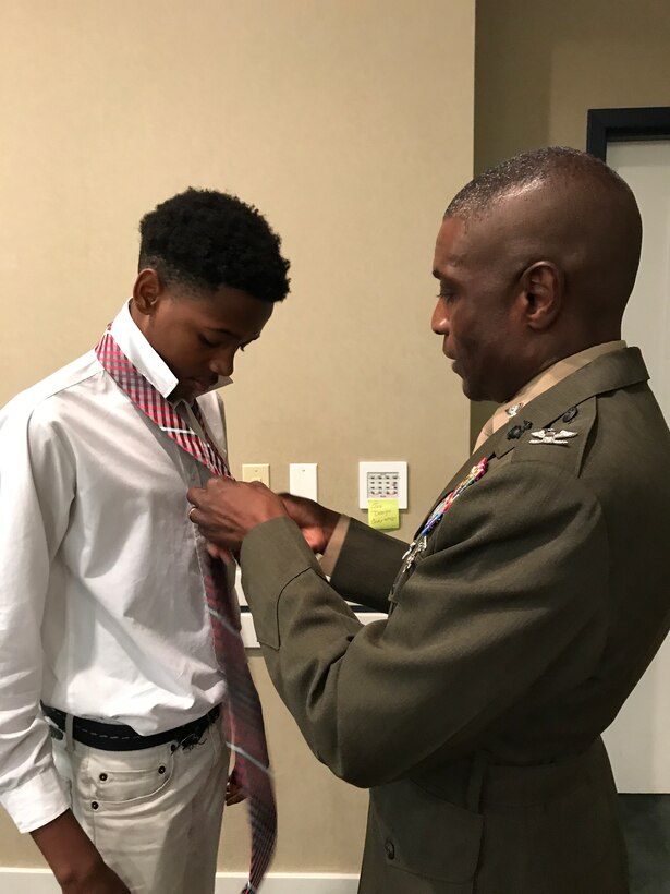 Col. James C. Carroll III, commanding officer, Marine Corps Logistics Base Albany, teaches a young man how to properly tie a necktie during the 5th annual “Ties that Bind” event.  The mentoring event teaches young boys to tie a necktie while forming bonds with some of the community’s most distinguished leaders at the Phoebe Northwest Conference Center in Albany, Ga., June 15.  The annual event, hosted by Phoebe Putney Memorial Hospital’s Network of Trust School Health Program, selects 50 boys, mostly from homes without fathers, and pairs them with 50 local men.  