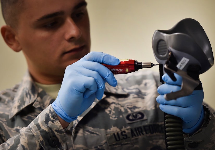 Airman 1st Class Ion Radu, 437th Operation Support Squadron aircrew flight equipment, inspects a helmet and oxygen mask at Joint Base Charleston, S.C., June 20. Airmen assigned to the 437th OSS AFE flight ensure that aircrew equipment including helmets, oxygen masks, life rafts, and parachutes are safe and ready for aircrew members to operate.