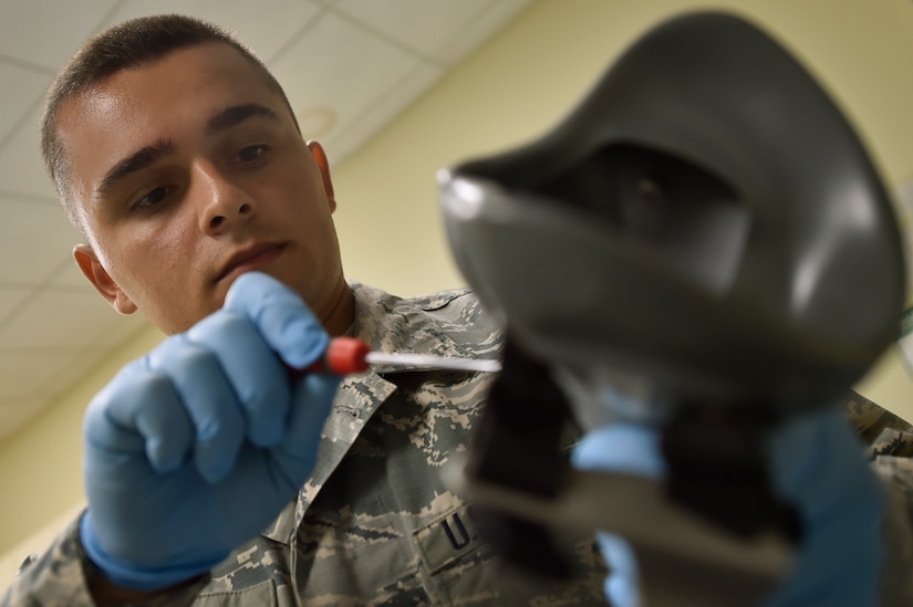 Airman 1st Class Ion Radu, 437th Operation Support Squadron aircrew flight equipment, inspects a helmet and oxygen mask at Joint Base Charleston, S.C., June 20. Airmen assigned to the 437th OSS AFE flight ensure that aircrew equipment including helmets, oxygen masks, life rafts, and parachutes are safe and ready for aircrew members to operate.