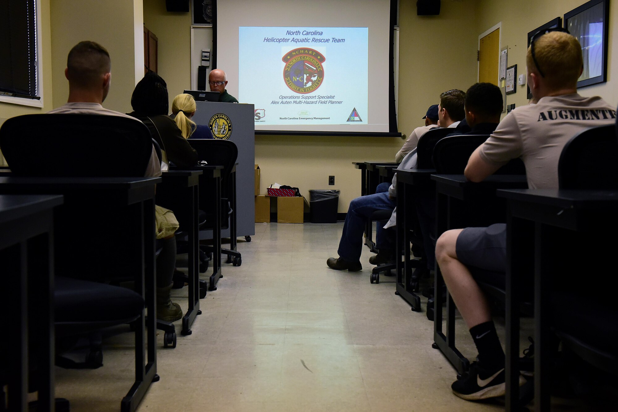 A group of survival, evasion, resistance and escape augmentees from the 4th Fighter Wing attend a North Carolina Helicopter Aquatic Rescue Team briefing led by Alex Auten, NC Emergency Management multi-hazard field planner, before observing a training exercise, July 20, 2017, at the NC State Highway Patrol Precision Driver's Training Facility, Raleigh, North Carolina. In order to become a SERE augmentee, the Airmen need to pass the SERE physical ability and stamina test, a water survival training course as well as a combat survival training course. (U.S. Air Force photo by Airman 1st Class Kenneth Boyton)