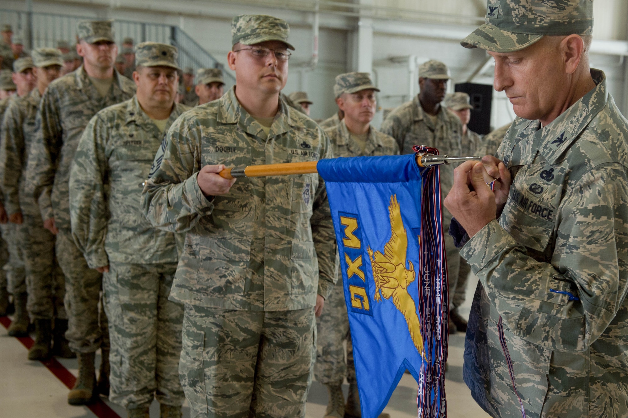 U.S. Air Force Col. Todd Andre, 1st Maintenance Group commander, hangs a streamer for a meritorious unit award during the 1st Fighter Wing Change of Command ceremony at Joint Base Langley-Eustis, Va., June 23, 2017. U.S. Air Force Col. Peter Fesler relinquished command after two years of service. (U.S. Air Force photo/Senior Airman Derek Seifert)