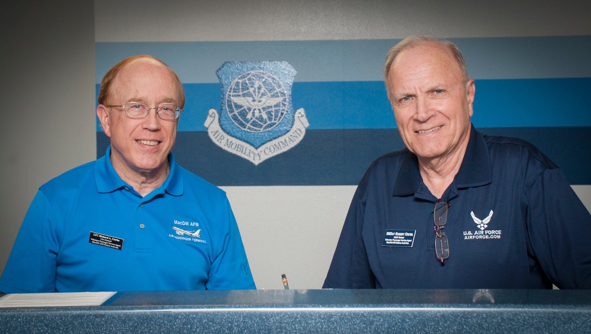 Retired U.S. Army Lt. Col Richard Gorka, left, and retired U.S. Air Force Senior Master Sgt. Robert Krowl, right, both volunteers at the passenger terminal, pause for a photo at the passenger terminal at MacDill Air Force Base, Fla., June 21, 2017. The passenger terminal has 16 volunteer veterans who assist with customer service. (U.S. Air Force photo by Airman 1st Class Mariette Adams)