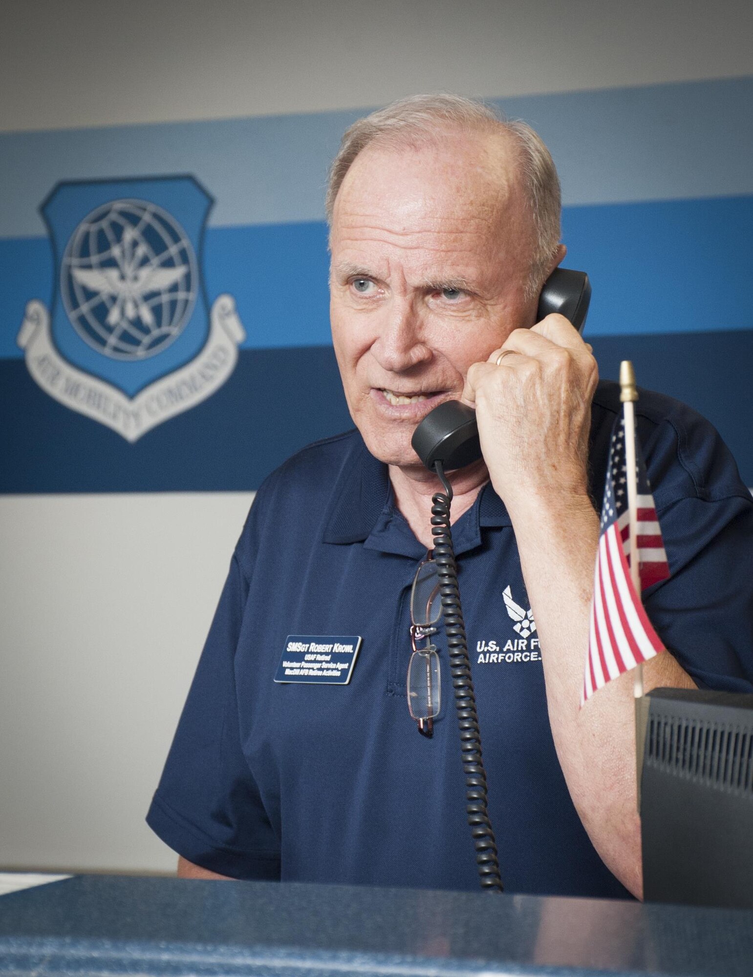 Retired U.S. Air Force Senior Master Sgt. Robert Krowl, a volunteer at the passenger terminal, answers a question over the phone at MacDill Air Force Base, Fla., June 21, 2017. The veteran volunteers at the passenger terminal assist customers and ensure they have essential information about space available flights. (U.S. Air Force photo by Airman 1st Class Mariette Adams)