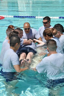 Airmen from the 944th Medical Squadron place a simulated patient onto a backboard during first responder water training May 31, 2017. The training also included a scenario with an adult “dummy” who sustained multiple injuries and a child “dummy” who broke a leg and fell into the pool. The training was conducted to promote pool safety during the 101 critical days of summer and to ensure Airmen are combat ready. (U.S. Air Force photo/Staff Sgt. Lausanne Kinder)