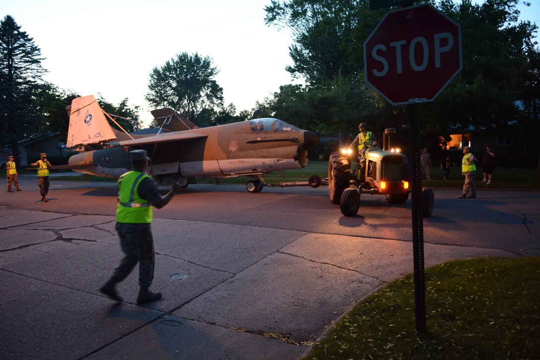 Members of the 115th Fighter Wing Crash, Disaster or Disabled Aircraft Recovery Team in coordination with Wausau city officials, police and city workers move a 1969 A-7 Corsair II aircraft through the streets of Wausau behind a 1966 John Deere 4020 tractor June 13, 2017 in Wausau, Wis. 