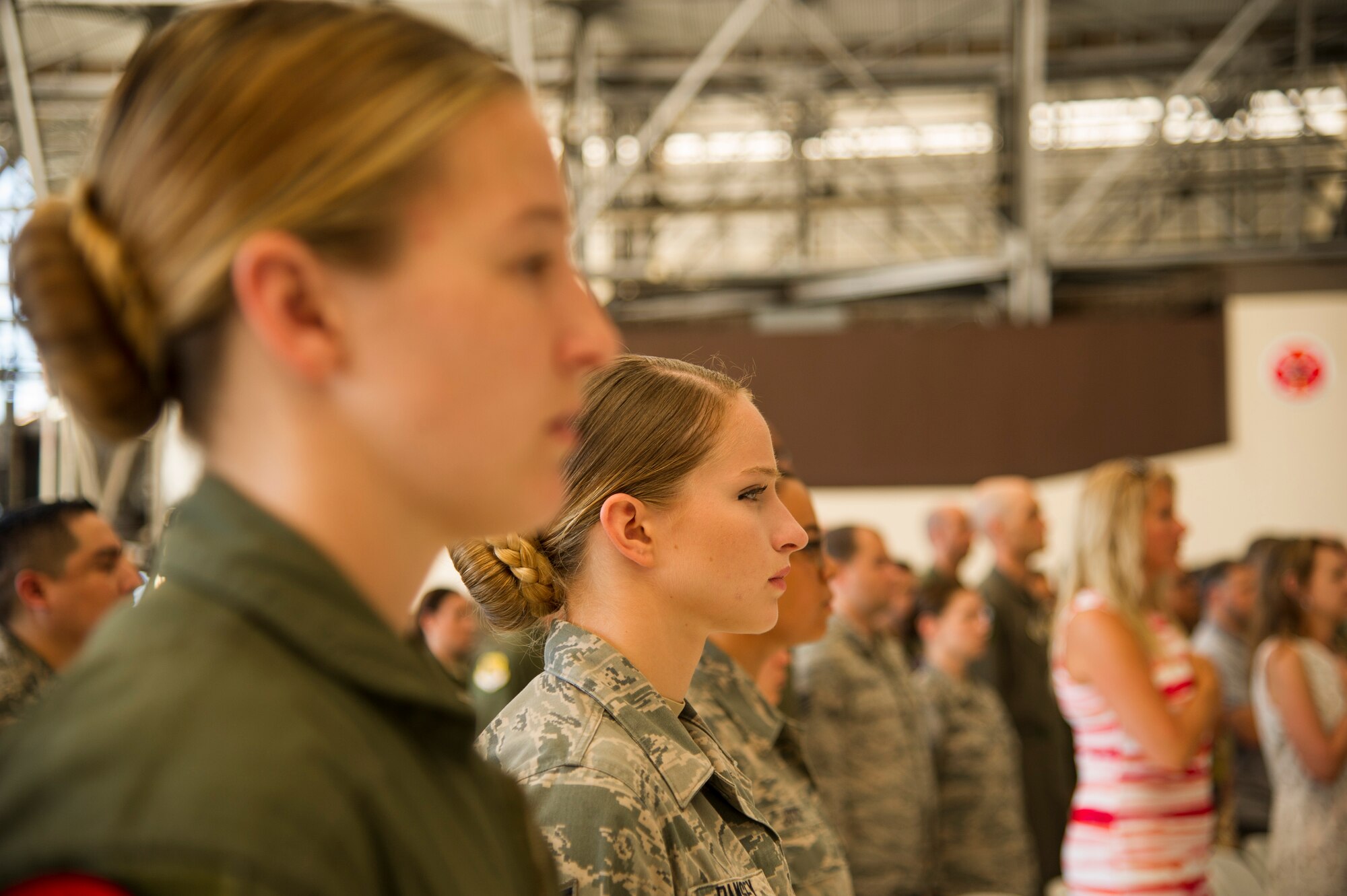 Personnel assigned to the 15th Operations group and family members stand for the National Anthem and the Hawaii Pono'i during the 15th Operations Group Change of Command Ceremony, Joint Base Pearl Harbor-Hickam, Hawaii, June 22, 2017. The 15th Operations Group oversees operations at the largest joint-use airflield in the U.S., executes global combat and peace time operations, and provides executive airlift for senior military leaders.  (U.S. photo by Tech. Sgt. Heather Redman)