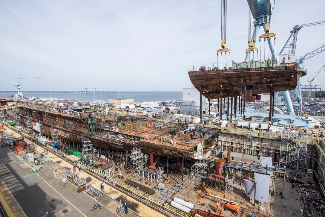 A crane moves the lower stern into place on the nuclear-powered aircraft carrier USS John F. Kennedy at Newport News Shipbuilding in Virginia, June 22, 2017. The John F. Kennedy, the second Gerald R. Ford-class aircraft carrier, is 50 percent structurally complete. Navy photo by John Whalen