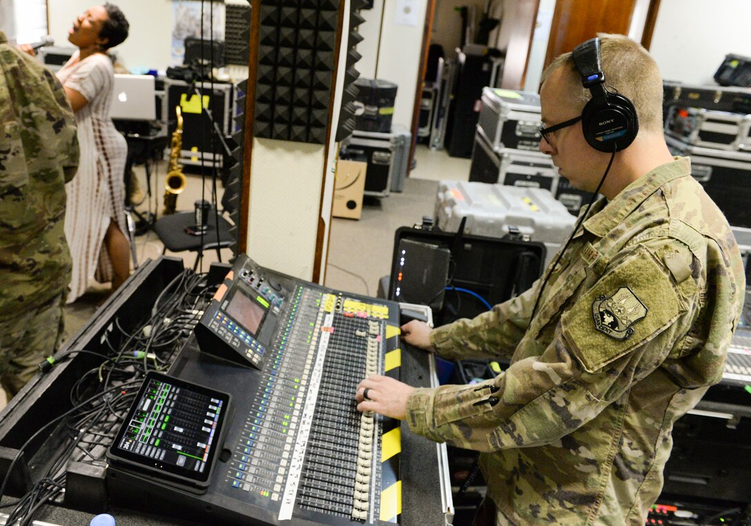 U.S. Air Force Airman 1st Class Daniel McCoy, audio engineer assigned to the Air Force Central Command Band, adjusts the sound board during a band practice held in preparation for a concert with Melinda Doolittle, background left, at Al Udeid, Air Force Base, Qatar, May 25, 2017. The AFCENT Band, stationed at Al Udeid, travels throughout the Central Command Area of Responsibility in support of building partnerships, boosting morale, and providing diplomacy and outreach to host nation communities. (U.S. Air Force photo by Tech. Sgt. Bradly A. Schneider/Released)
