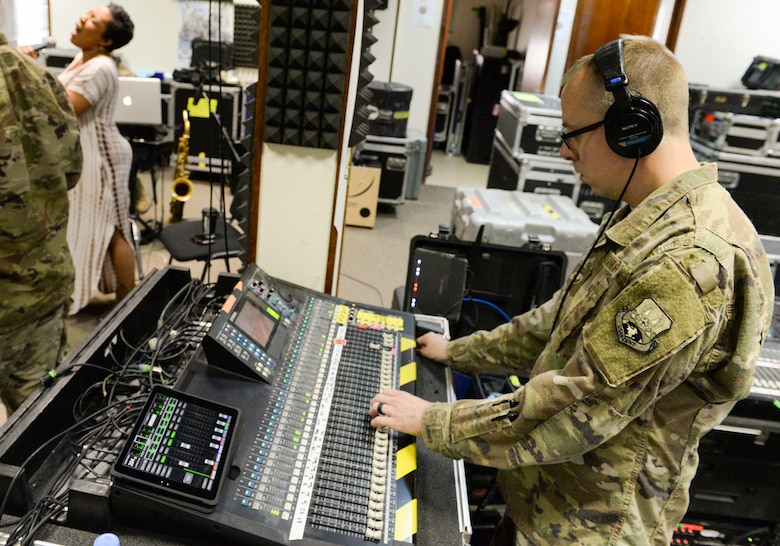 U.S. Air Force Airman 1st Class Daniel McCoy, audio engineer assigned to the Air Force Central Command Band, adjusts the sound board during a band practice held in preparation for a concert with Melinda Doolittle, background left, at Al Udeid, Air Force Base, Qatar, May 25, 2017. The AFCENT Band, stationed at Al Udeid, travels throughout the Central Command Area of Responsibility in support of building partnerships, boosting morale, and providing diplomacy and outreach to host nation communities. (U.S. Air Force photo by Tech. Sgt. Bradly A. Schneider/Released)