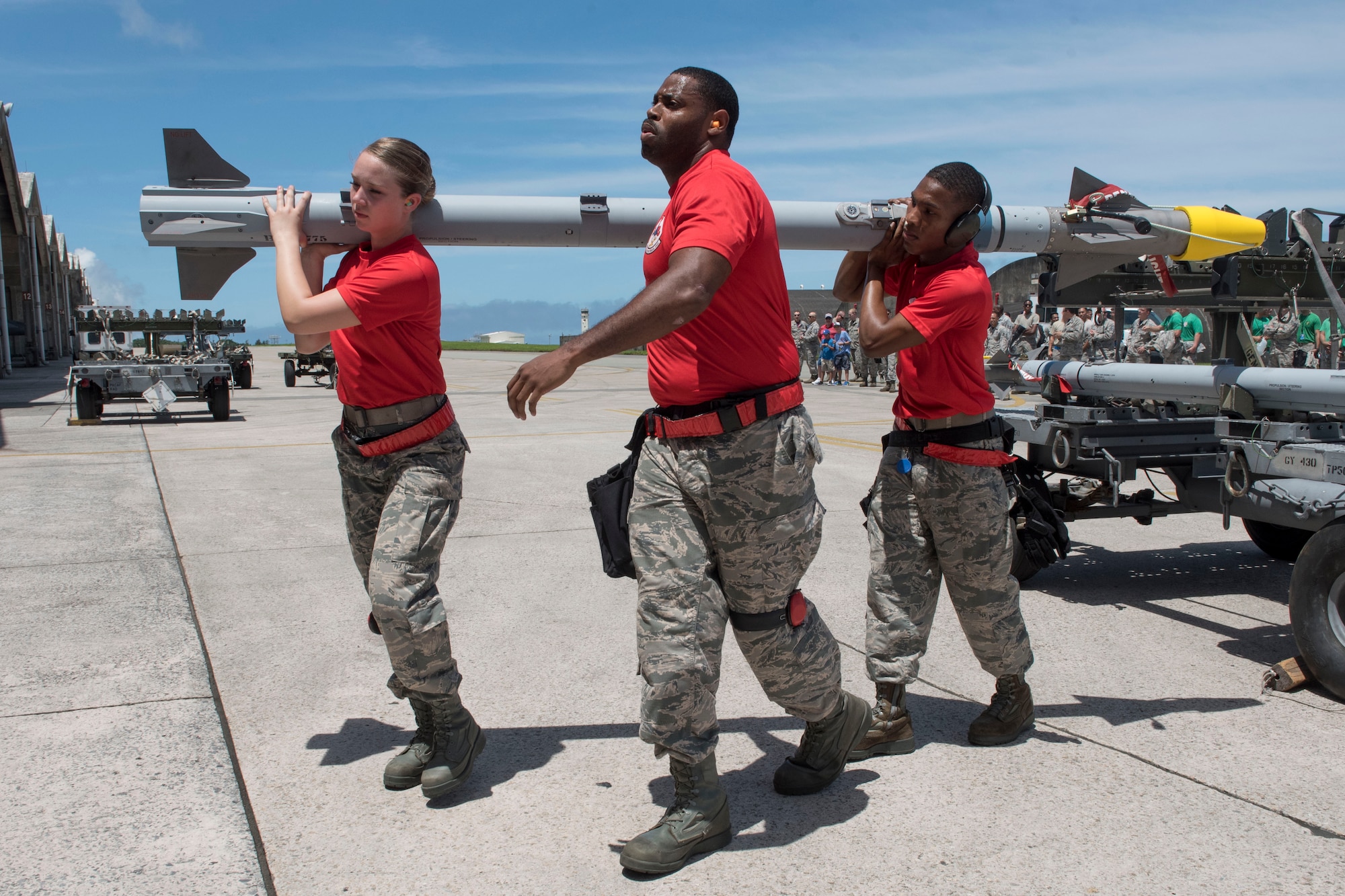 A weapons load team from the 67th Aircraft Maintenance Unit carries an AIM-9 sidewinder missile toward an F-15 Eagle fighter aircraft during a quarterly weapons load competition June 23, 2017, at Kadena Air Base, Japan. The competition pitted two load crews against each other to evaluate who could prepare the aircraft for combat the fastest and with the fewest procedural errors. (U.S. Air Force photo by Senior Airman John Linzmeier)