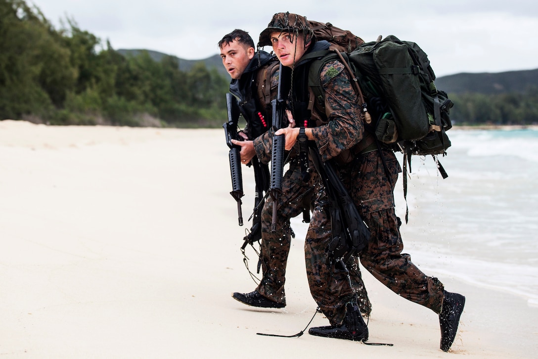 Marines Corps Cpl. Kyle Smith, foreground, and Cpl. Samuel Perry walk onto a beach after a two kilometer fin swim during an amphibious exercise at Marine Corps Training Area Bellows, Hawaii, June 15, 2017. Kyle and Perry are raider reconnaissance team operators assigned to the 3rd Radio Reconnaissance Platoon, 3rd Radio Battalion. Marine Corps photo by Lance Cpl. Luke Kuennen