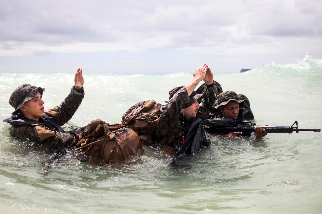 Marine Corps Lance Cpl. Shane Springstead, left, Cpl. Ryan Ehlers, center, and Lance Cpl. Armanie Singletary give a signal to team members on the beach at Marine Corps Training Area Bellows, June 15, 2017. The signal indicates that there were no casualties during the team’s insertion. The Marines are raider reconnaissance team operators assigned to the 3rd Radio Reconnaissance Platoon, 3rd Radio Battalion. Marine Corps photo by Lance Cpl. Luke Kuennen