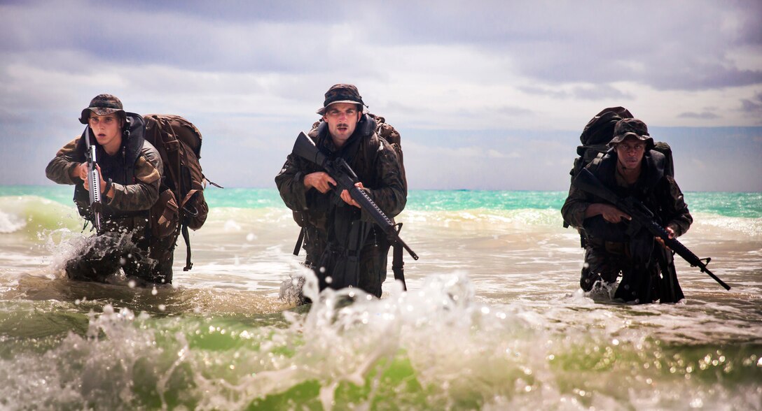 Marine Corps Lance Cpl. Shane Springstead, left, Cpl. Ryan Ehlers, center, and Lance Cpl. Armanie Singletary emerge from the ocean during an amphibious exercise at Marine Corps Training Area Bellows, Hawaii, June 15, 2017. The Marines are raider reconnaissance team operators assigned to the 3rd Radio Reconnaissance Platoon, 3rd Radio Battalion. Securing the beach is part of the training during the 13-week reconnaissance raider operator’s course. Marine Corps photo by Lance Cpl. Luke Kuennen