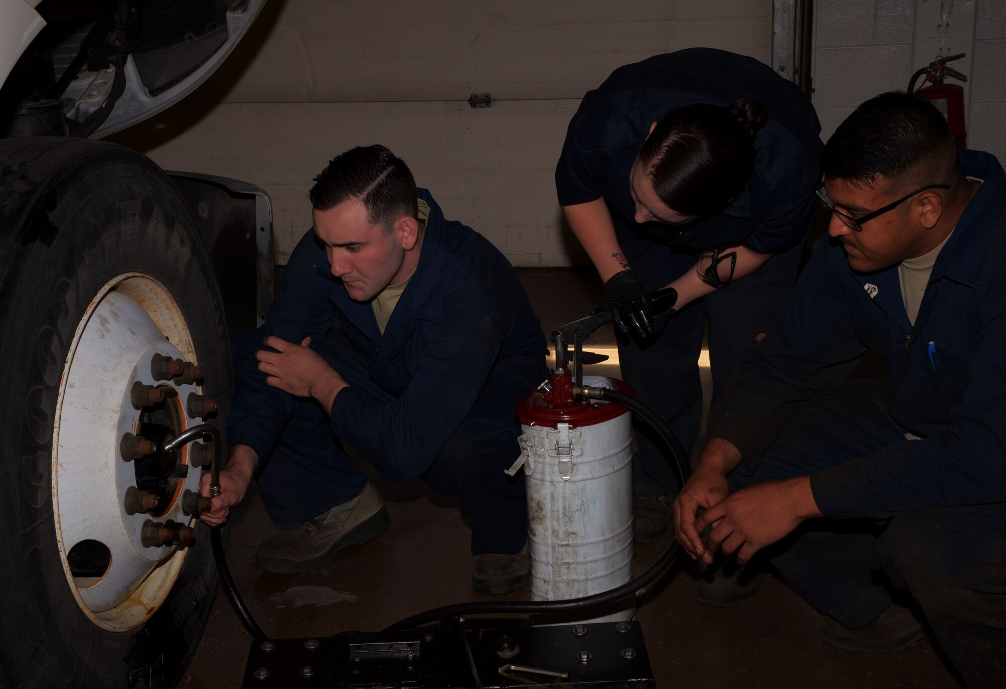 From left, Airman Michael Winter, Senior Airman Virginia Bludworth and Airman Steven Velasquez, 5th Logistics Readiness Squadron vehicle maintainers, fill wheel hubs with oil on a freightliner tractor at Minot Air Force Base, N.D., June 19, 2017. The unit is responsible for the maintenance of roughly 1,295 vehicles. (U.S. Air Force photo by Airman 1st Class Dillon J. Audit)