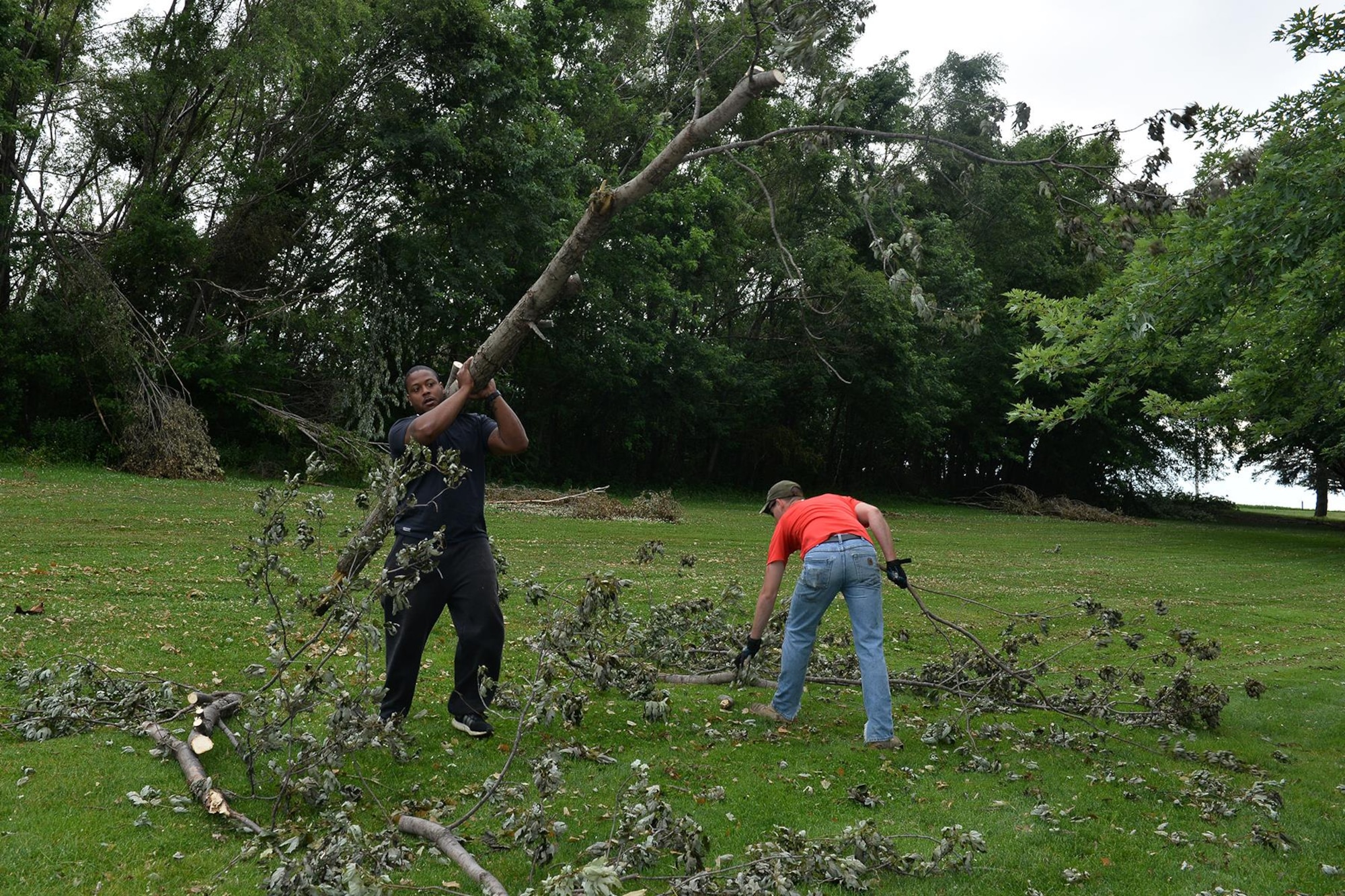 U.S. Air Force Staff Sgt. Jahmal Hardy, 55th Security Forces Squadron, carries a broken tree limb during the Willow Lake golf course cleanup on Offutt AFB, Neb., June 23. Hardy and other members of Team Offutt volunteered to help clean up the golf course following a powerful storm that hit the base June 16. The storm produced EF1 and EF2 tornadoes and caused significant damage to parts of Offutt AFB. (U.S. Air Force photo by Charles Haymond)