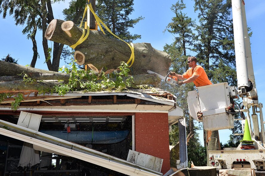 Matthew Morgan, a grounds maintenance crewman, removes a tree from a garage behind General Rows on Offutt AFB, Neb., June 20. A fast moving storm with driving rain, high winds and two confirmed tornadoes caused significant damage to the base on June 16. Property damage occurred to various facilities, homes and some aircraft, but no base personnel were injured. The storm also damaged many trees and caused wide-spread power outages. Base officials estimate it could take months before the entire base is fully repaired. (U.S. Air Force photo by Charles Haymond)