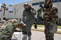 U.S. Air Force Reserve Staff Sgt. Casey Godwin, removes protective booties from Staff Sgt. Aaron Broge, loadmaster, 327th Airlift Squadron, as Tech. Sgt. David Underwood holds a manifold/blower and intercom unit during decontamination training June 19, 2017, at Little Rock Air Force Base, Ark. Godwin and Underwood are aircrew flight equipment specialists assigned to the 913th Operations Support Squadron and took part in the training to enhance their skills in protecting personnel and their abilities to work safely and effectively in a contaminated environment. (U.S. Air Force photo by Master Sgt. Jeff Walston/Released)