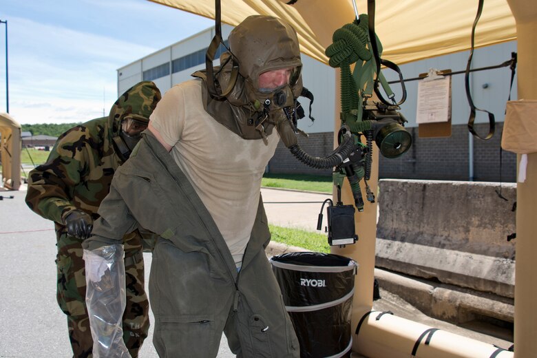 U.S. Air Force Reserve Tech. Sgt. David Underwood, aircrew flight equipment (AFE) specialist, 327th Operations Support Squadron, removes a flight suit from Staff Sgt. Aaron Broge, loadmaster, 327th Airlift Squadron, at Station 7: (Protective Overgarment Removal), during decontamination training June 19, 2017, at Little Rock Air Force Base, Ark. The AFE Airmen conducted training to enhance their skills in protecting personnel and their abilities to work safely and effectively in a contaminated environment. (U.S. Air Force photo by Master Sgt. Jeff Walston/Released)