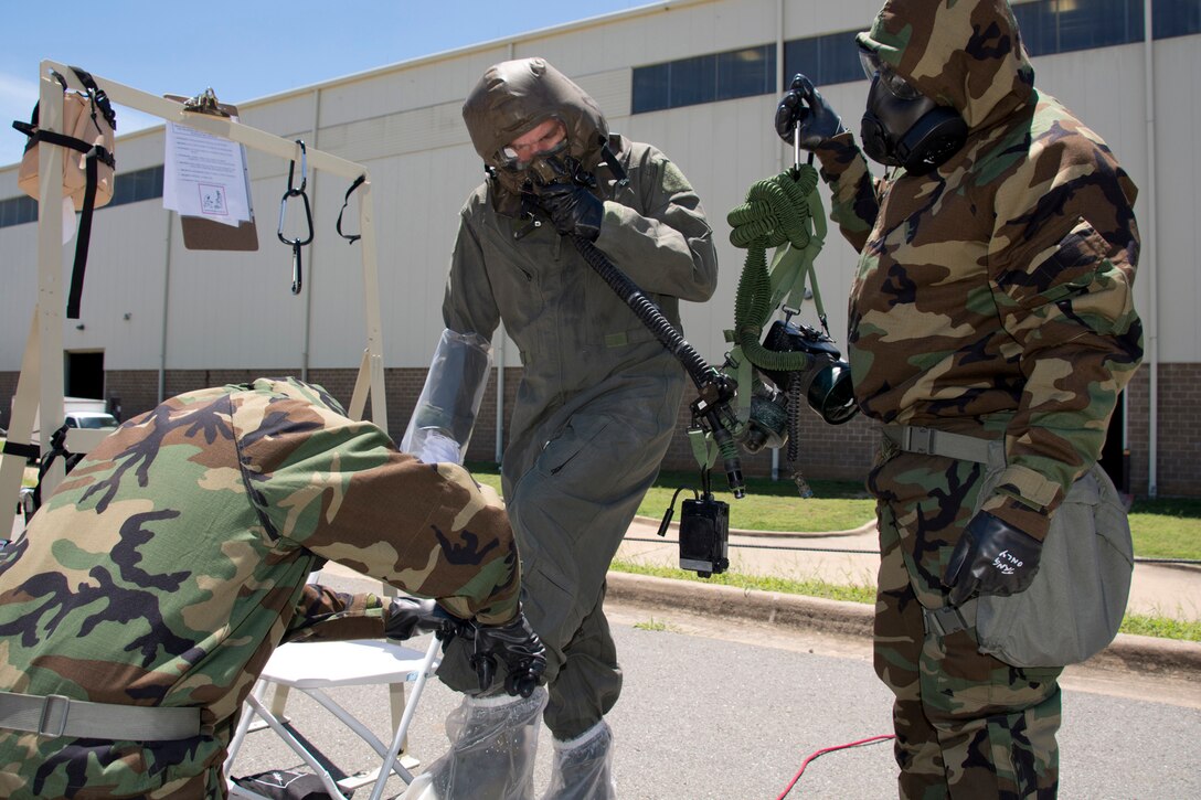 Air Force Reserve Staff Sgt. Casey Godwin removes protective booties from Staff Sgt. Aaron Broge, a loadmaster with the 327th Airlift Squadron, as Tech. Sgt. David Underwood holds a manifold/blower and intercom unit during decontamination training June 19, 2017, at Little Rock Air Force Base, Ark. Godwin and Underwood are aircrew flight equipment specialists assigned to the 913th Operations Support Squadron. Air Force photo by Master Sgt. Jeff Walston