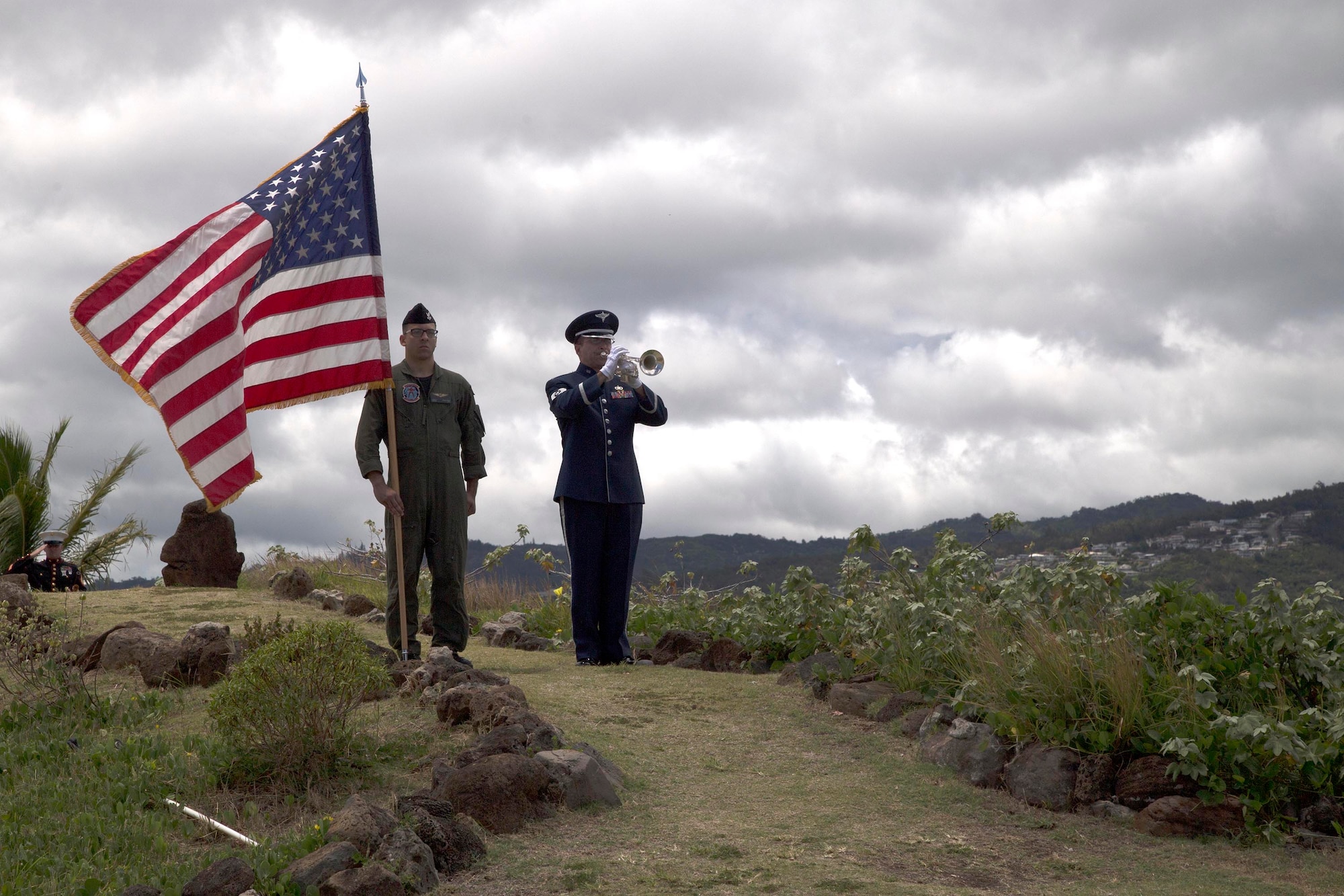 Naval Air Crewman (Avionics) 2nd Class Corey Robinson, assigned to Fleet Air Reconnaissance Squadron Three, holds a flag while Tech. Sgt. Noah Barry plays Taps during the Crew 4 memorial ceremony in Honolulu. (U.S. Navy photo by Petty Officer 1st Class Cody R. Boyd)