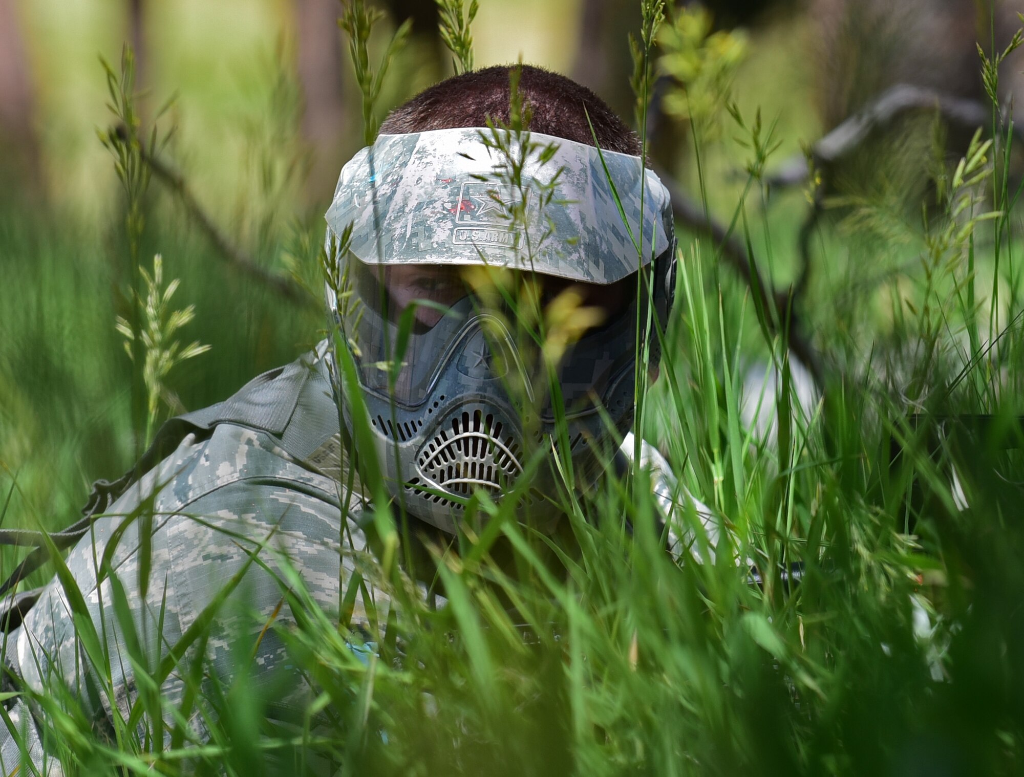 An Airman assigned to the 28th Civil Engineer Squadron uses tall grass as concealment during a U.S. Army led field training at a South Dakota National Guard training site June 19, 2017. The Airmen wore paintball masks as both sides wielded paintball guns to replicate live combat reactions. (U.S. Air Force photo by Senior Airman James L. Miller)