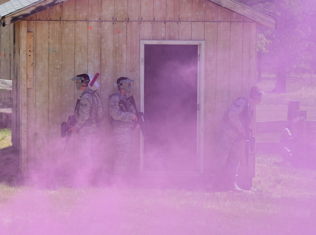A squad of 28th Civil Engineer Squadron Airmen stand behind a breached building waiting for smoke to dissipate in a mock village at a South Dakota National Guard training site June 19, 2017. The Airmen used a culmination of their training to execute orders to clear a simulated village of adversaries and locate a weapons cache. (U.S. Air Force photo by Senior Airman James L. Miller)