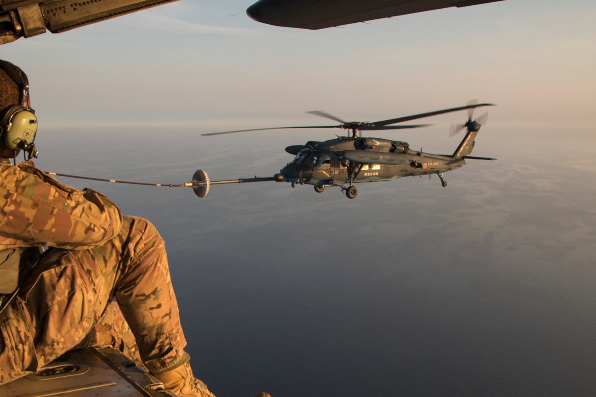 A U.S. Air Force loadmaster from the 353rd Special Operations Group observe a Japan Air Self-Defense Force UH-60J Black Hawk helicopter assigned to the Komatsu Air Rescue Squadron above the Sea of Japan, June 19, 2017, during Exercise Teak Jet. This is the first time that members of the 353rd SOG held HAAR training at night with JASDF members in Honshu Island in Japan. Exercise Teak Jet is a joint combined exchange training (JCET) focused on improving interoperability between U.S. Air Force and Japan Air Self-Defense Force. (U.S. Air Force photo by Yasuo Osakabe)