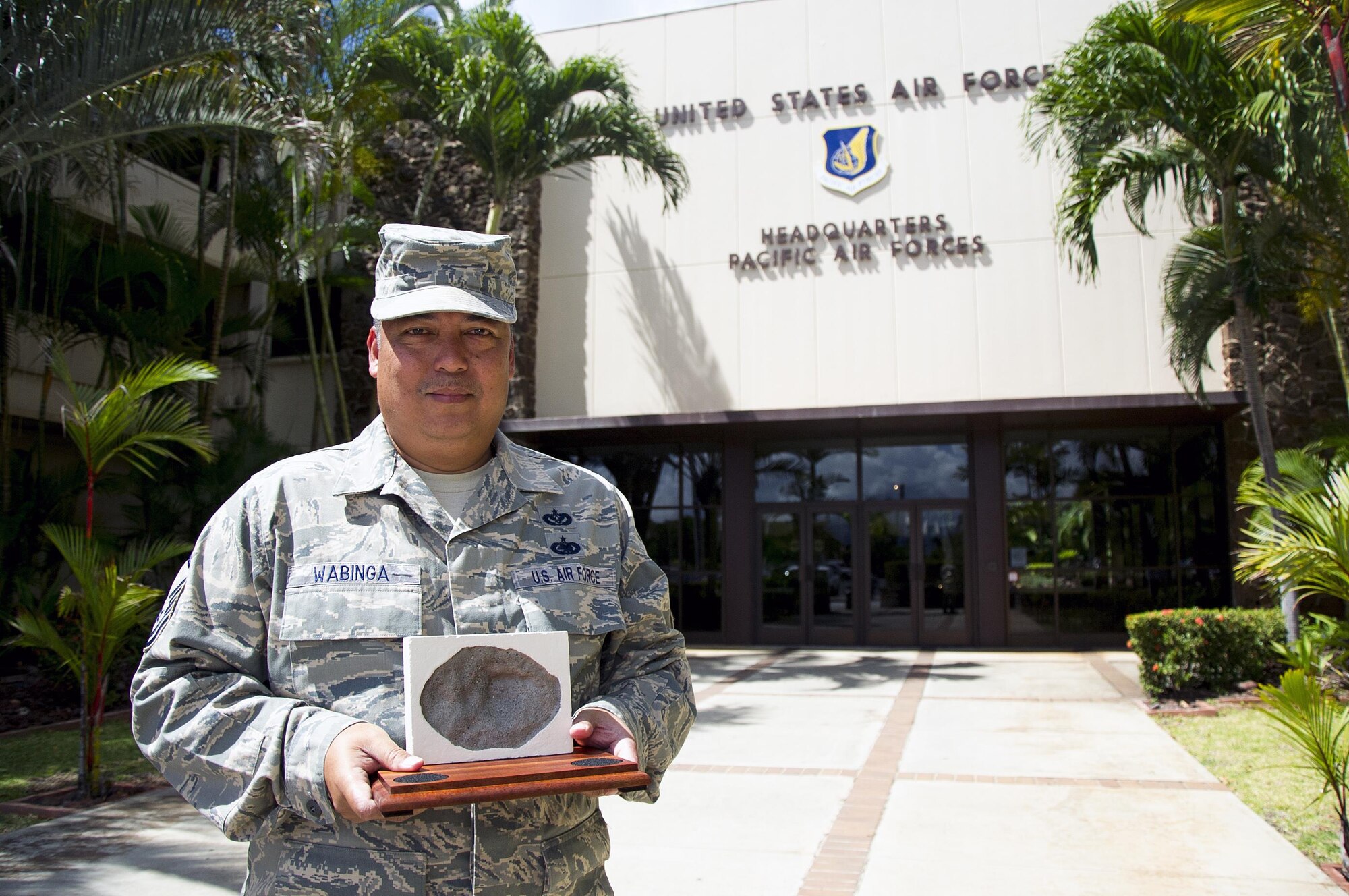 U.S. Air Force Master Sgt. Ronald Wabinga, of Kapa'a, Kauai, a member of the 624th Civil Engineer Squadron, displays a replication of a bullet-hole mark, or pockmark, caused by bomb shrapnel from the Imperial Japanese attack on Oahu Dec. 7, 1941 at the Pacific Air Forces Headquarters, Joint Base Pearl Harbor-Hickam, Hawaii, April 13, 2017. Wabinga spends his free time making these farewell gifts to help people remember Hawaii and the men and women who gave their lives for their country. (U.S. Air Force photo by Master Sgt. Theanne K. Herrmann)