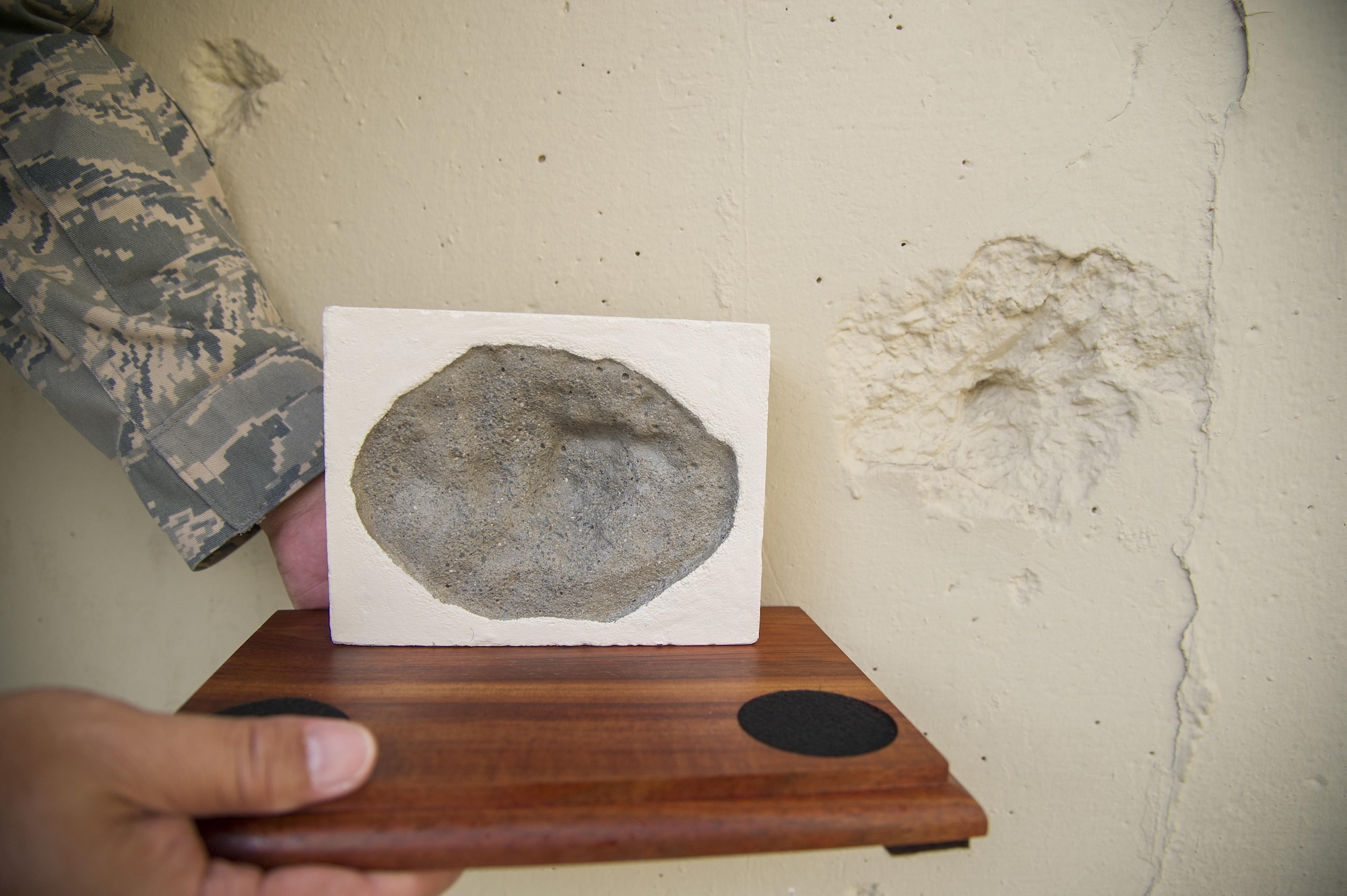 U.S. Air Force Master Sgt. Ronald Wabinga, of Kapa'a, Kauai, a member of the 624th Civil Engineer Squadron displays a replication of a bullet-hole mark, or pockmark, caused by bomb shrapnel from the Imperial Japanese attack on Oahu Dec. 7, 1941 at the Pacific Air Forces Headquarters, Joint Base Pearl Harbor-Hickam, Hawaii, April 13, 2017. Wabinga spends his free time making these farewell gifts to help people remember Hawaii and the men and women who gave their lives for their country. (U.S. Air Force photo by Master Sgt. Theanne K. Herrmann)