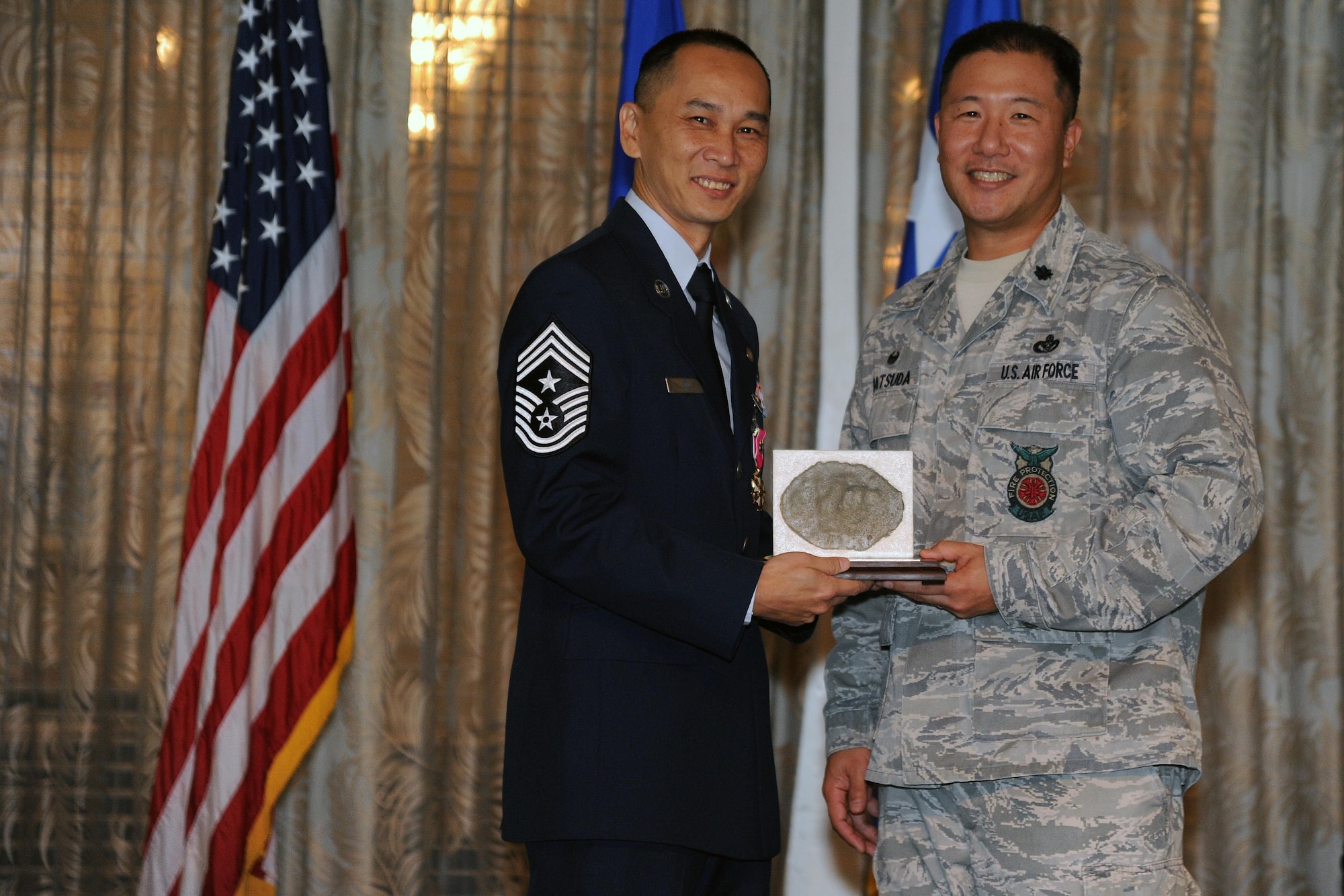 U.S. Air Force Command Chief Master Sgt. Michael Du, of Walnut, Calif., accepts a farewell gift from Lt. Col. Reid Matsuda, commander of the 624th Civil Engineer Squadron's Airmen, during his retirement ceremony at the Historic Hickam Officers Club, Joint Base Pearl Harbor-Hickam, Hawaii, Feb. 11, 2017. The gift is a replica of one of the bullet-hole markings, or pockmark, caused by bomb shrapnel from the Pacific Air Forces Headquarters building. The PACAF building was targeted during the Imperial Japanese attack on Oahu December 7, 1941. Master Sgt. Ronald Wabinga, a member of the 624th CES, spends his free time making farewell gifts to help people remember Hawaii and the men and women who gave their lives for their country. (U.S. Air Force photo by Master Sgt. Theanne K. Herrmann)