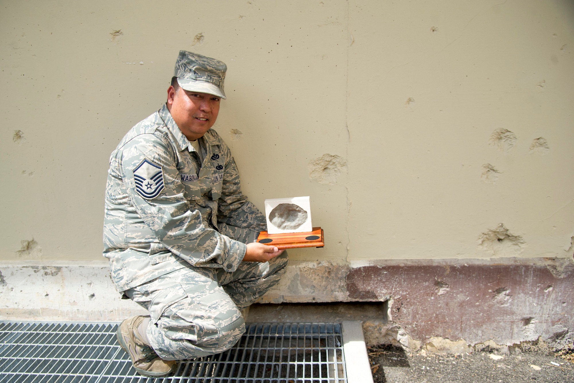 U.S. Air Force Master Sgt. Ronald Wabinga, of Kapa'a, Kauai, a member of the 624th Civil Engineer Squadron, displays a replication of a bullet-hole mark, or pockmark, caused by bomb shrapnel from the Imperial Japanese attack on Oahu Dec. 7, 1941 at the Pacific Air Forces Headquarters, Joint Base Pearl Harbor-Hickam, Hawaii, April 13, 2017. Wabinga spends his free time making these farewell gifts to help people remember Hawaii and the men and women who gave their lives for their country. (U.S. Air Force photo by Master Sgt. Theanne K. Herrmann)