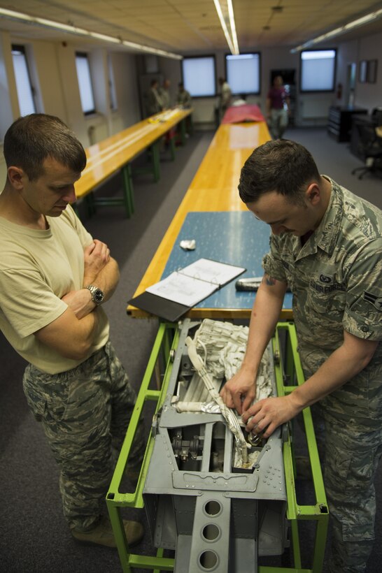 U.S. Air Force Lt. Col. Joshua Kubacz, left, 52nd Operations Support Squadron commander, learns how to pack an ejection chair parachute from Airman 1st Class Austin Lebrun, right, 52nd OSS aircrew flight equipment technician, during the commander’s parachute shop familiarization tour at Spangdahlem Air Base, Germany, June 23, 2017. The aircrew flight equipment shop inspects and maintains survival gear for aircrew such as parachutes, chemical protective clothing, survival suits, helmets, and life rafts. (U.S. Air Force photo by Senior Airman Preston Cherry)