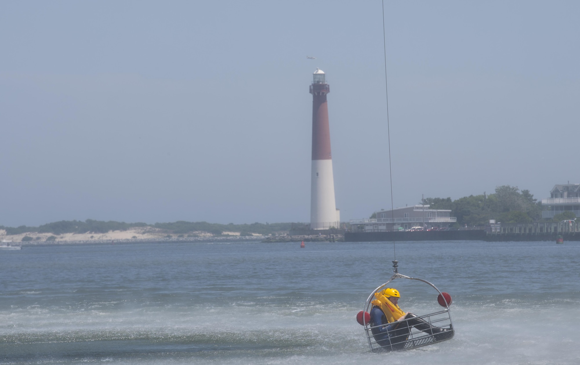An Airman from the 305th Air Mobility Wing sits in a rescue basket during water survival training in Barnegat, N.J. June 22. The Airmen were raised in the basket by a U.S. Coast Guard helicopter, there to assist in the training. (U.S. Air Force photo by Senior Airman Joshua King