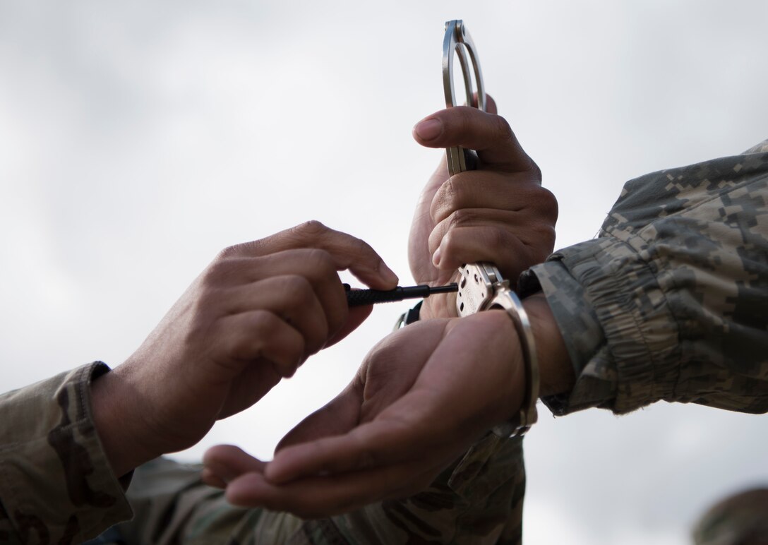 A U.S. Army Reserve military police with the 300th MP Brigade practices unlocking handcuffs during Guardian Justice at Fort McCoy, Wisconsin, June 24. Guardian Justice is a functional exercise, broken down into two-week cycles, centered on squad and team-level training with a focus on internment, resettlement, detainee operations and combat support. During each two-week cycle, Soldiers train on internment operations, weapons qualification, biometrics, reflexive fire, Military Operations on Urbanized Terrain (MOUT), non-lethal Tasers, MP battle drills and include a situational training exercise. (U.S. Army Reserve photo by Sgt. Audrey Hayes)
