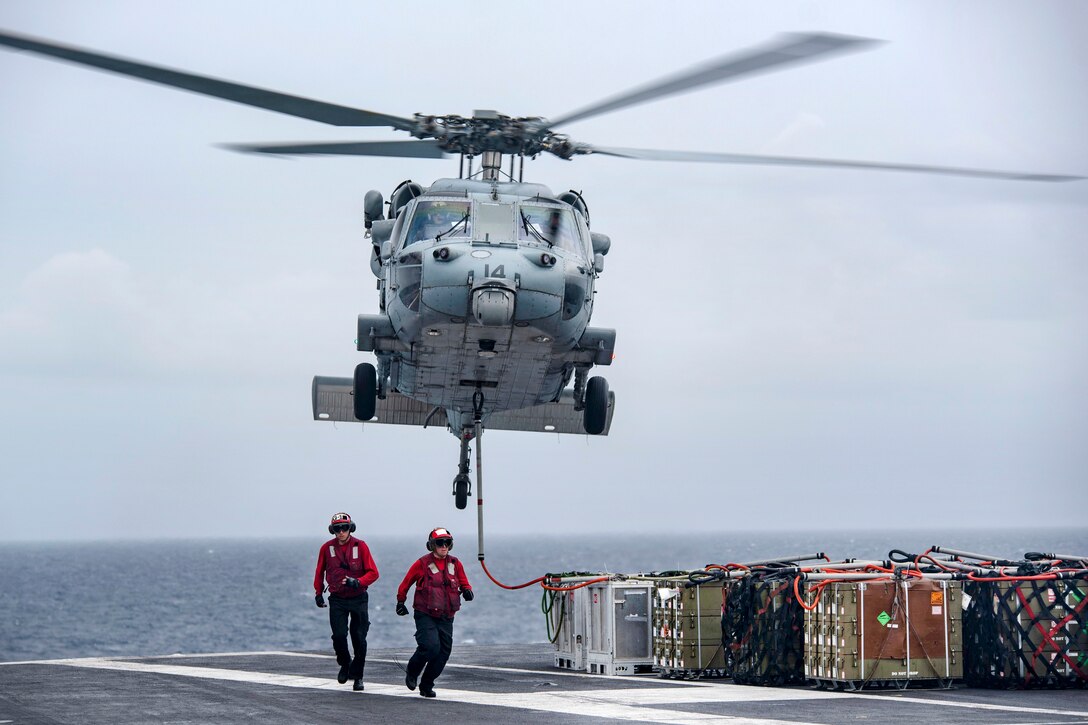 Aviation ordnance sailors move to a safe distance as a Navy MH-60S Sea Hawk helicopter lifts ammunition crates from the flight deck of the aircraft carrier USS Dwight D. Eisenhower during an ammunition offload with the dry cargo and ammunition ship USNS Medgar Evers in the Atlantic Ocean, June 21, 2017. The helicopter crew is assigned to Helicopter Sea Combat Squadron 7. Navy photo by Petty Officer 3rd Class Nathan T. Beard