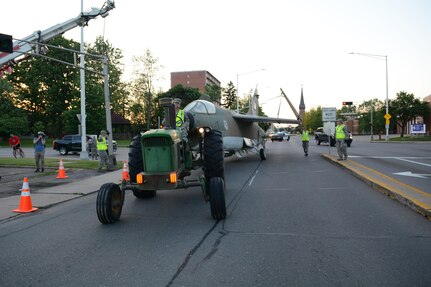 Members of the 115th Fighter Wing Crash, Disaster or Disabled Aircraft Recovery Team in coordination with Wausau city officials, police and city workers move a 1969 A-7 Corsair II aircraft through the streets of Wausau behind a 1966 John Deere 4020 tractor June 13, 2017 in Wausau, Wis. 