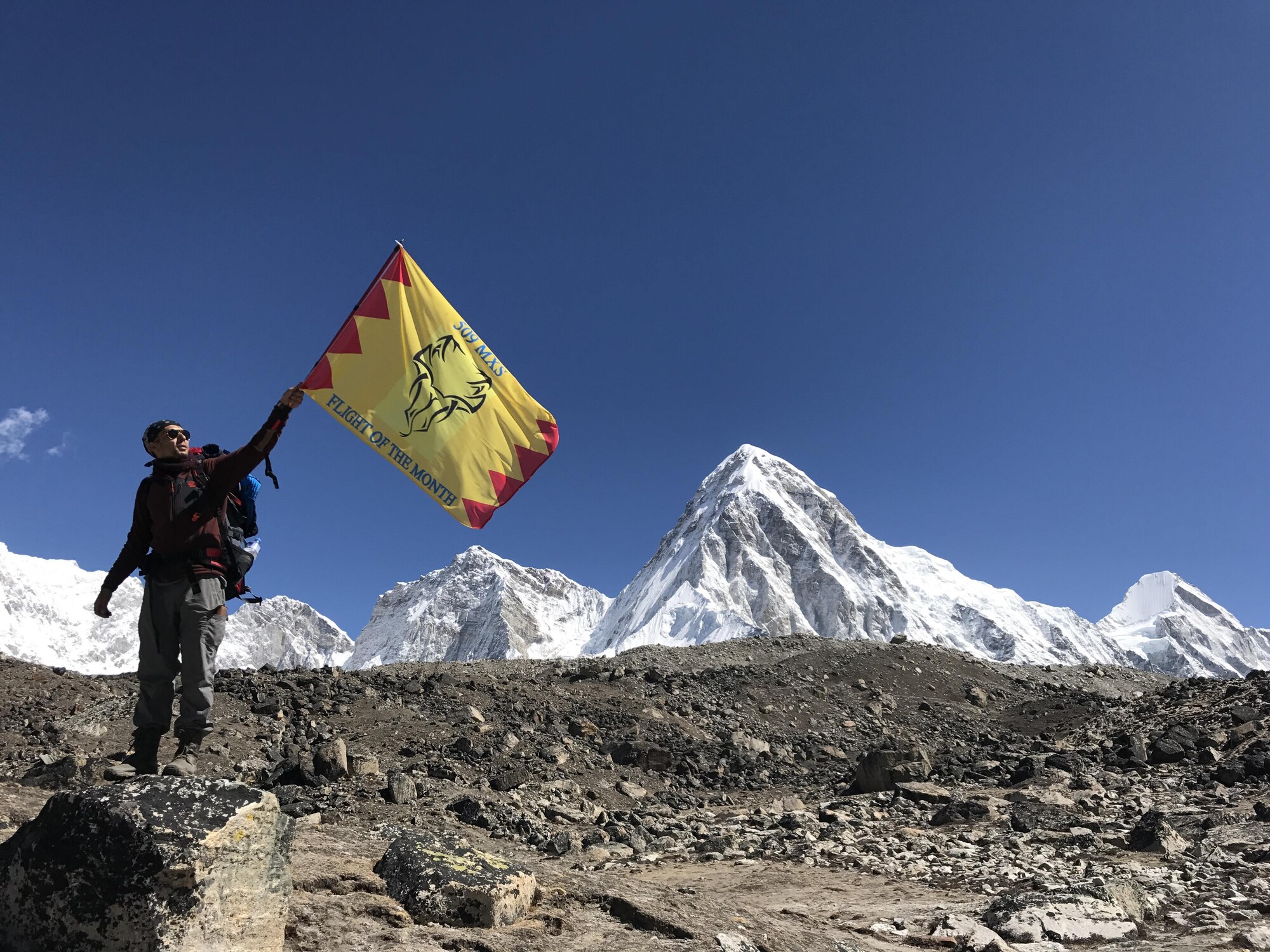 Senior Airman Sukh Bhandari, an aerospace ground equipment journeyman of the 509th Maintenance Squadron, stands with the squadron’s deployment flag at Mount Everest South Base Camp May 20, 2017.  This base camp is located at an altitude of approximately 17,500 feet in Nepal. Along with Bhandari, Airman 1st Class Anish Chauhan and Senior Airman Shane Hoag, both water and fuel systems management journeymen of the 509th Civil Engineer Squadron, made the hike as well. (courtesy photo)