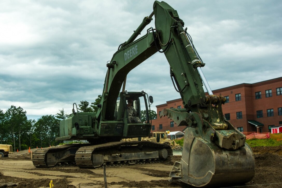 Maine Army National Guard Sgt. Kory Peckham, a heavy construction equipment operator with the 262nd Engineer Company (Horizontal), operates an excavator at the Raymond Elementary School in Raymond, Maine, June 24, 2017. The engineers turned a slope into a flat base for a multipurpose field as part of a training project that will benefit the school and surrounding community. Maine Army National Guard photo by Sgt. Sarah Myrick