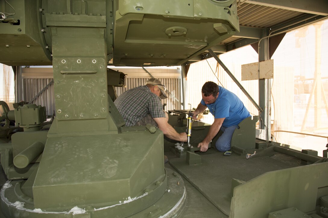 (Left) Heavy Equipment Mechanics Mack Brown and Patrick Jackett from Production Plant Albany, Ga., work atop an LAV-ATM learning to install the Modified Target Acquisition System turret looming over them, June 15. The MTAS is capable of acquiring a target and tracking it while moving so that the Tube-Launched Optically-tracked Wire-guided missile, or TOW, can knock out an enemy tank from nearly two miles away. Artisans from PPA as well as Production Plant Barstow are training at the Marine Depot Maintenance Command facility aboard the Yermo Annex of Marine Corps Logistics Base Barstow.