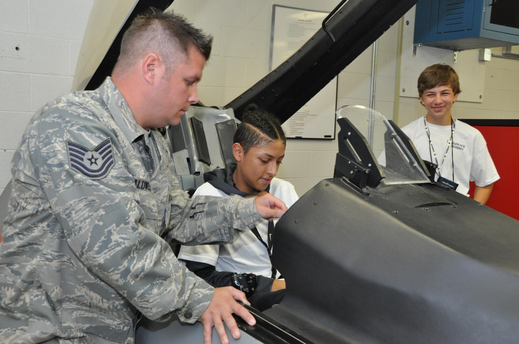 Tech. Sgt. Tanner Caldwell, 301st Operations Support Flight Aircrew Flight Equipment craftsman, demonstrates a portion of the egress simulator that F-16 pilots receive as their annual training requirements. Eighteen students from the Dallas Aviation Career Education (ACE) Academy visited the 301st Fighter Wing, Navy and Marines at Naval Air Station Fort Worth Joint Reserve Base, Texas, June 8, 2017, for a tour designed to educate them on different aspects of the military. The ACE Academy has been actively involving eighth through 12th grade students in Science, Technology, Engineering and Math (STEM) activities since the early 1990s. (U.S. Air Force photo by Ms. Julie Briden-Garcia)
