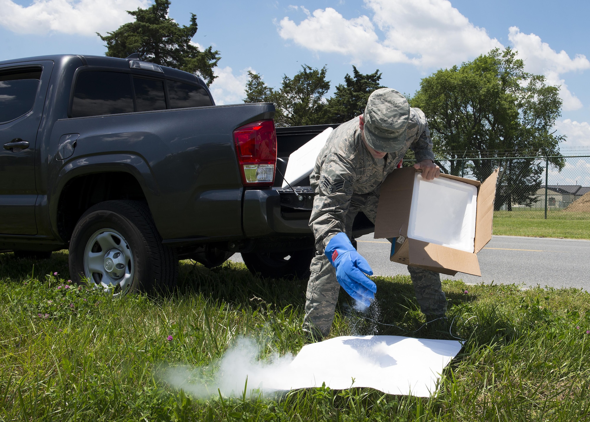 Senior Airman Moss Purcell, 436th Aerospace Medicine Squadron public health technician, applies dry ice to a piece of white cloth June 9, 2017, at Dover Air Force Base, Del. Dry ice, which is comprised of frozen carbon dioxide, is used as bait to attract ticks. (U.S. Air Force photo by Senior Airman Zachary Cacicia)
