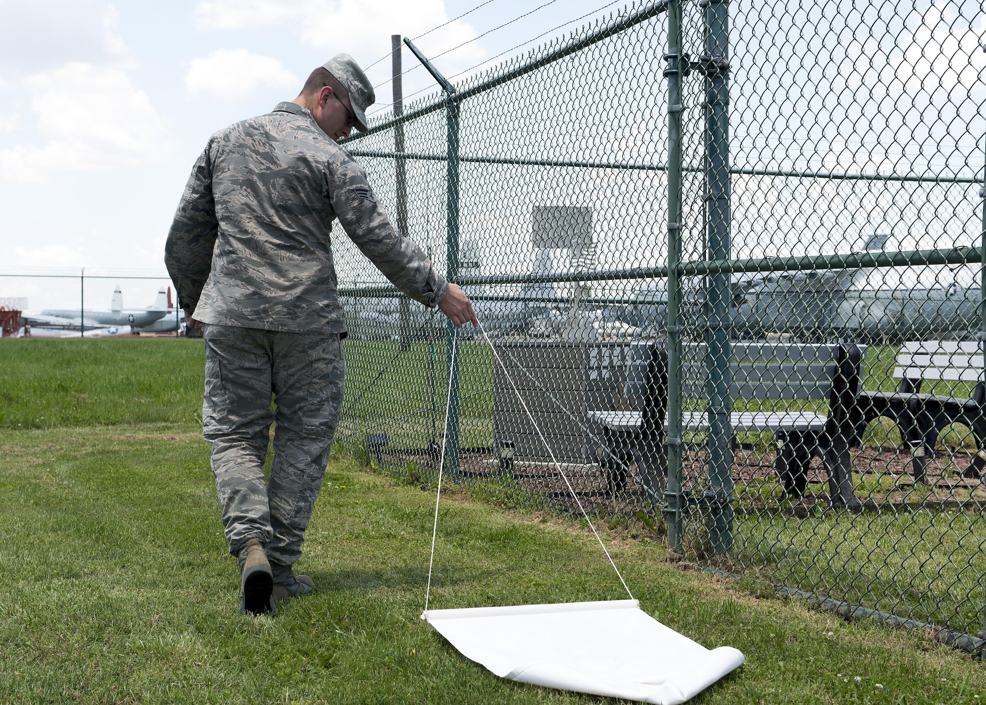 Senior Airman Moss Purcell, 436th Aerospace Medicine Squadron public health technician, drags a piece of white cloth through a grassy field attempting to capture ticks June 9, 2017, at Dover Air Force Base, Del. Certain species of ticks are capable of carrying Lyme disease and are able to infect humans and other animals. (U.S. Air Force photo by Senior Airman Zachary Cacicia)