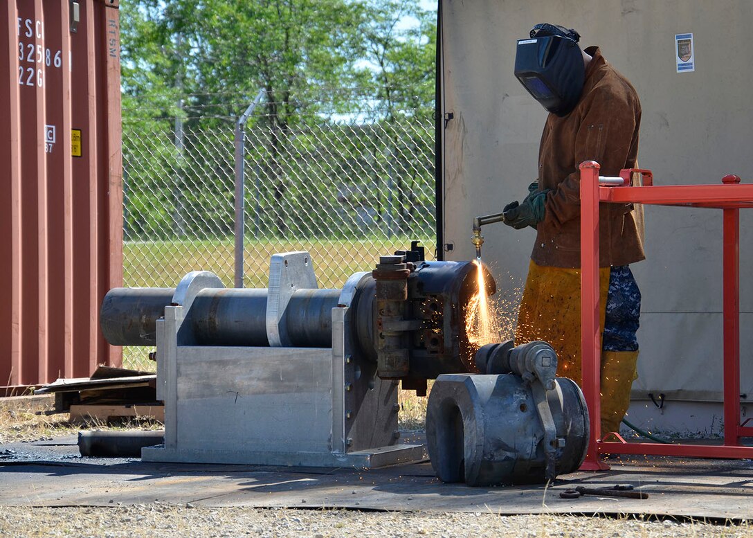 Navy Logistics Specialist 1st Class Jesus Martinez demilitarizes a 122 mm howitzer gun turned in by Detroit Arsenal.