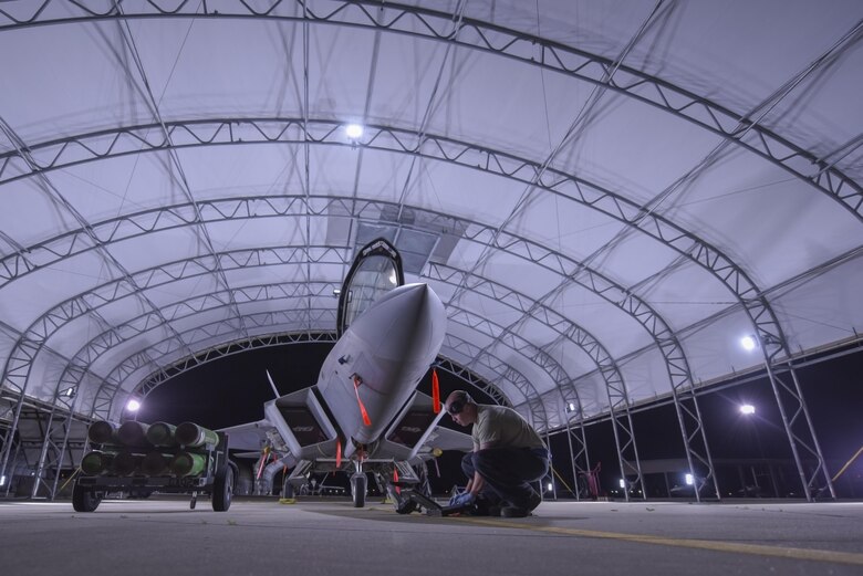 A U.S. Air Force crew chief assigned to the 27th Fighter Wing  performs a check on an F-22 Raptor at Joint Base Langley-Eustis, Va., June 27, 2017. The newly built, sun shelters have built-in lights that illuminate the aircraft, all of which are ran solely on solar power. (U.S. Air Force photo/Airman 1st Class Tristan Biese)