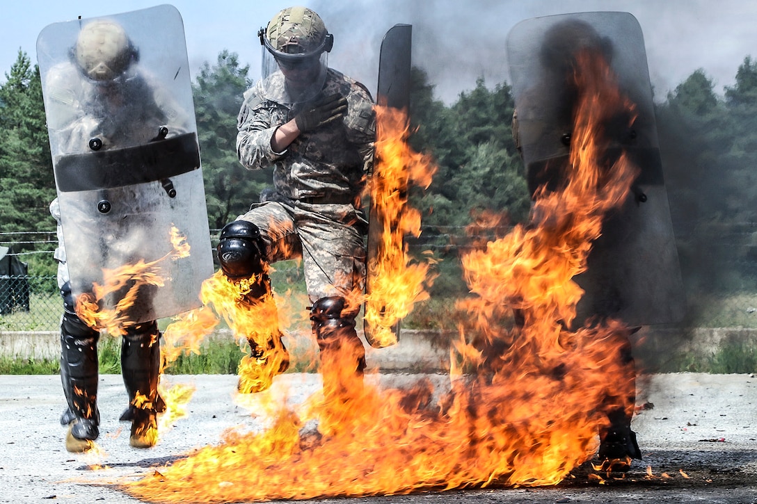Paratroopers jump and wave their shields to extinguish equipment fires during training at the Joint Multinational Readiness Center in Hohenfels, Germany, June 23, 2017. Army photo by Staff Sgt. Nicholas Farina
