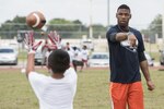 Terrance Williams, Dallas Cowboys wide receiver, throws a pass to a child during a youth football camp June 26, 2017, at Joint Base San Antonio-Randolph. JBSA-Randolph was one of 11 military communities selected to host a 2017 ProCamps football event. (U.S. Air Force photo by Senior Airman Stormy Archer)