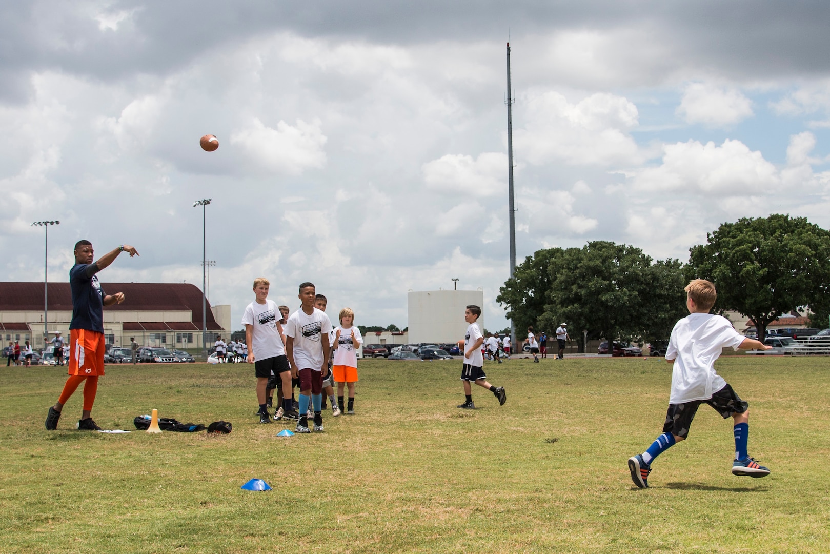 Terrance Williams, Dallas Cowboys wide receiver, throws a pass to a child during a youth football camp June 26, 2017, at Joint Base San Antonio-Randolph. JBSA-Randolph was one of the 11 military communities selected to host a 2017 ProCamps football event. (U.S. Air Force photo by Senior Airman Stormy Archer)